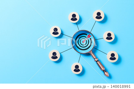 CRM, Customer Relationship Management and Target Audience Concept. A magnifying glass focusing on a target with interconnected wooden icons representing people, CRM, and audience targeting strategies. 140018991