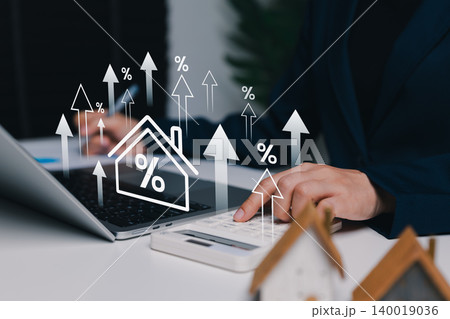 Mortgage rate increase and real estate finance concept. Person using calculator with virtual house, percent symbols, upward arrows. loan interest, property investment, housing cost, financial planning Mortgage rate increase and real estate finance concept. Person using calculator with virtual house, percent symbols, upward arrows. loan interest, property investment, housing cost, financial planning 140019036