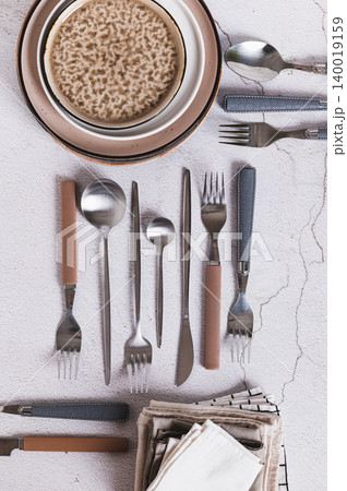Forks, spoons, knives, plates and napkins on the table top and vertical view Forks, spoons, knives, plates and napkins on the table top and vertical view 140019159