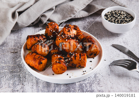Spicy sausage bites with garlic and sesame seeds on a plate on the table Spicy sausage bites with garlic and sesame seeds on a plate on the table 140019181