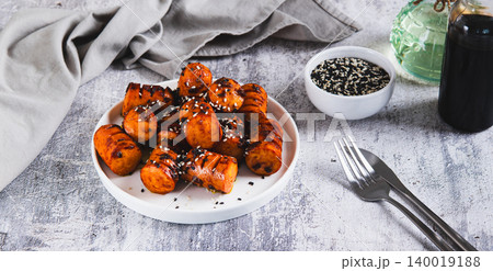Spicy sausages in soy sauce and sesame seeds on a plate on the table web banner 140019188