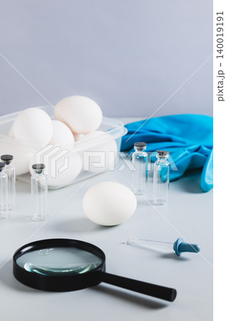 Salmonella concept, chicken egg, pipette and magnifying glass on the table vertical view 140019191