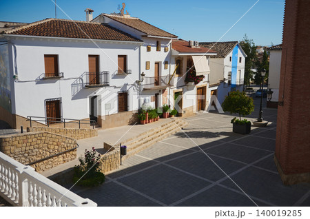 Woman traveling in a small Spanish village plaza with white houses and mountain views Woman traveling in a small Spanish village plaza with white houses and mountain views 140019285
