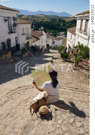 Woman holding map in a small Spanish village with cobblestone street and mountain views Woman holding map in a small Spanish village with cobblestone street and mountain views 140019312