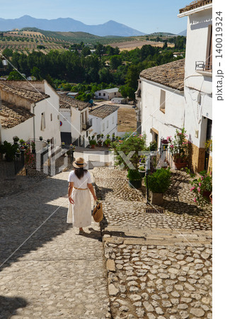 Woman traveling through a small Spanish village with cobblestone streets and mountain views 140019324