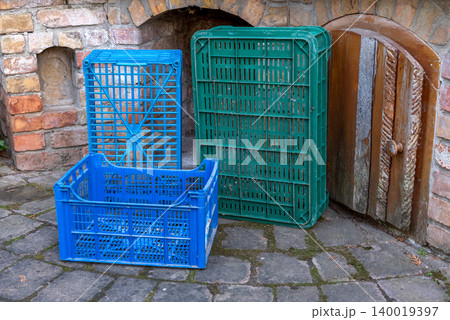 two green and one blue plastic crates in front of a brick wall two green and one blue plastic crates in front of a brick wall 140019397