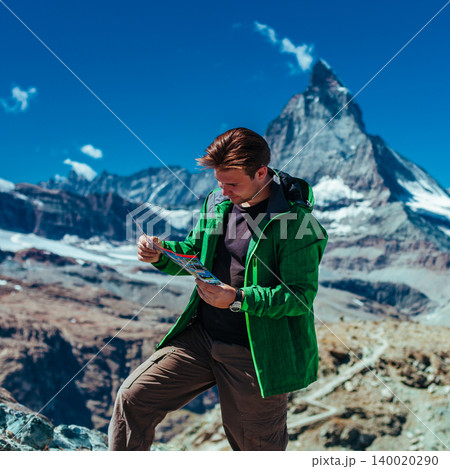 Tourist with map on Matterhorn mountain background in Swiss Alps Tourist with map on Matterhorn mountain background in Swiss Alps 140020290