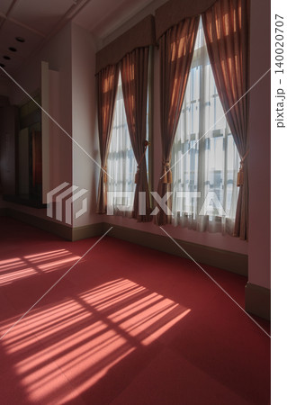赤いカーペットに窓から光が差し込む歴史建築の廊下の縦構図写真 140020707