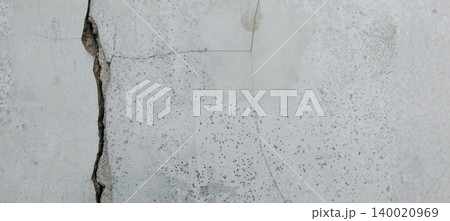 Close up of a gray concrete wall with large vertical cracks and a natural rough texture. 140020969