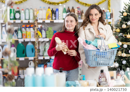 Woman with teen daughter buyer with filled basket household chemistry wanders around store Woman with teen daughter buyer with filled basket household chemistry wanders around store 140021730