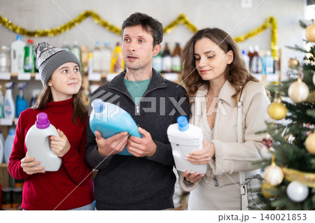 Couple man and woman with daughter choosing detergent in decorated store Couple man and woman with daughter choosing detergent in decorated store 140021853