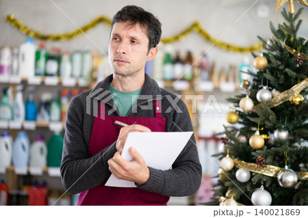 Male salesman makes notes on paper - keeps track of the receipt and expenditure of goods in supermarket Male salesman makes notes on paper - keeps track of the receipt and expenditure of goods in supermarket 140021869