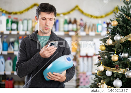 Adult man scanning qr code for detergent Adult man scanning qr code for detergent 140021887
