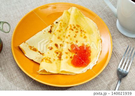 Tasty russian pancakes with red caviar at plate closeup Tasty russian pancakes with red caviar at plate closeup 140021939