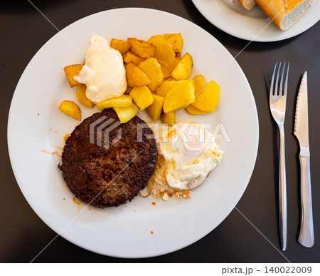 There is food for lunch on plate - two flat cutlets, French fries, fried eggs. There is food for lunch on plate - two flat cutlets, French fries, fried eggs. 140022009