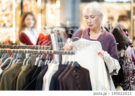 Senior woman at trading floor pick out and buying jacket 140022011