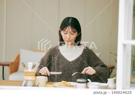 手作りの朝食を楽しむ一人暮らしの女性 手作りの朝食を楽しむ一人暮らしの女性 140024020