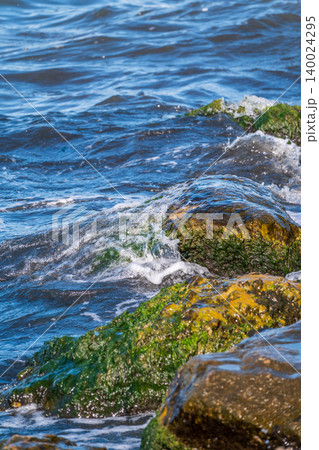 Sea water splashing over the stones on the beach 140024295