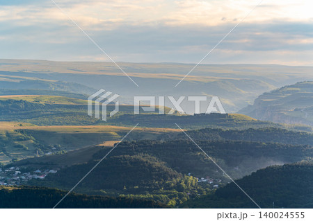 Layers of green mountains and hills in the haze during sunset. Panoramic View of Green hills and Meadow. 140024555