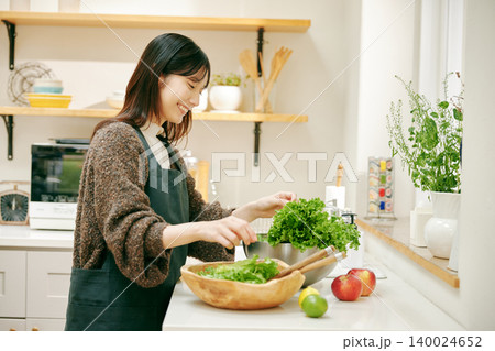 新鮮な野菜を使って料理をする女性 140024652