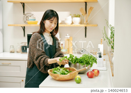 新鮮な野菜を使って料理をする女性 140024653