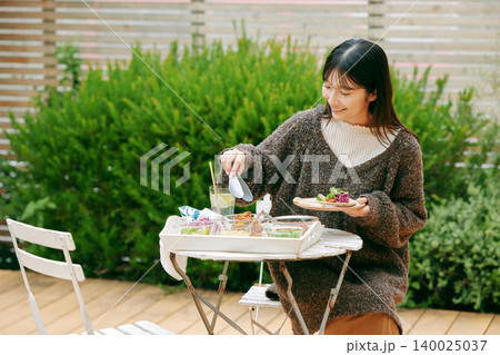 庭でタコスを食べる女性 140025037