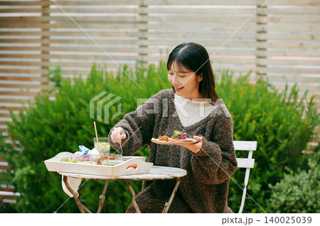 庭でタコスを食べる女性 140025039