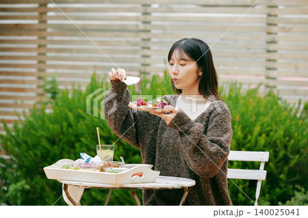 庭でタコスを食べる女性 140025041