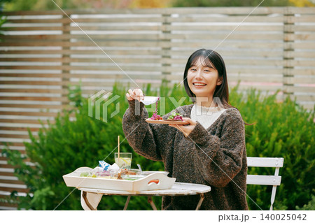 庭でタコスを食べる女性 140025042