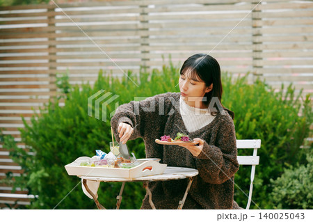 庭でタコスを食べる女性 140025043