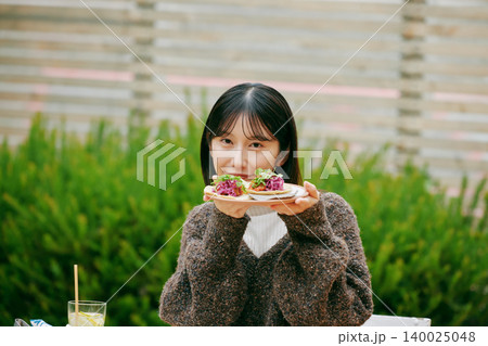 庭でタコスを食べる女性 庭でタコスを食べる女性 140025048