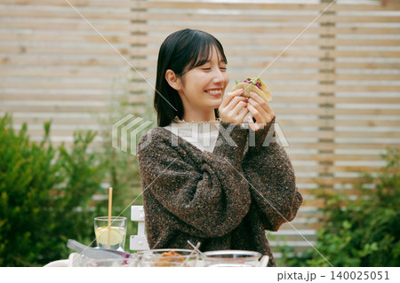 庭でタコスを食べる女性 140025051