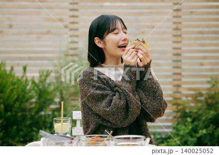 庭でタコスを食べる女性 庭でタコスを食べる女性 140025052