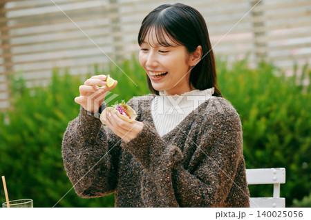 庭でタコスを食べる女性 140025056