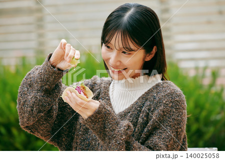 庭でタコスを食べる女性 140025058