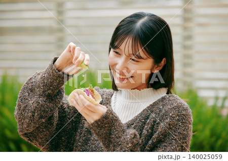 庭でタコスを食べる女性 140025059