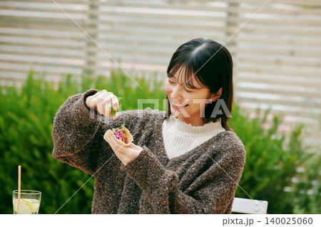 庭でタコスを食べる女性 140025060
