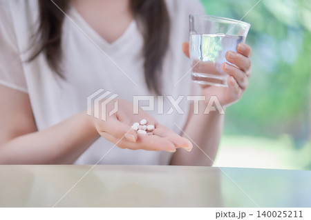 大量の薬を飲む20代女性 140025211