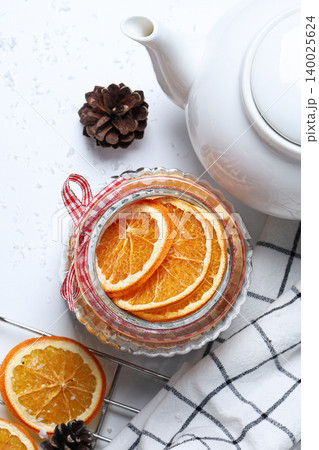 Dried orange slices in a jar next to a white teapot Dried orange slices in a jar next to a white teapot 140025624