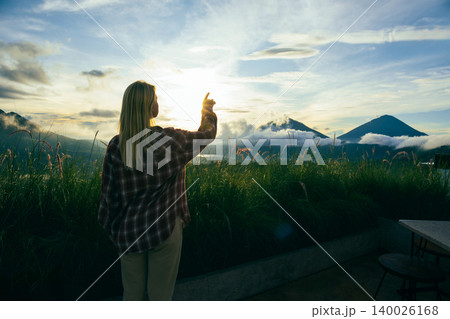 Traveler reaching towards the sunset in Kintamani Bali Traveler reaching towards the sunset in Kintamani Bali 140026168
