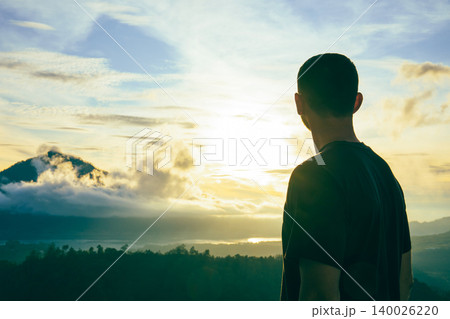 Man looks towards sunset over Kintamani area and lakes Man looks towards sunset over Kintamani area and lakes 140026220