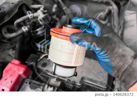A gloved hand holding a new car fuel filter 140026372