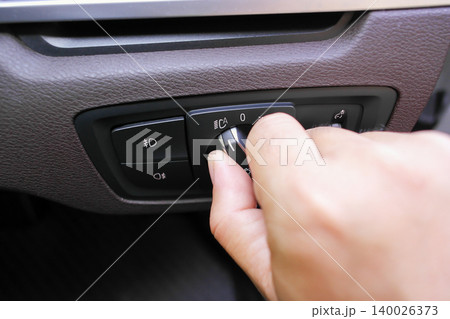 A hand turning the rotary headlight control switch A hand turning the rotary headlight control switch 140026373