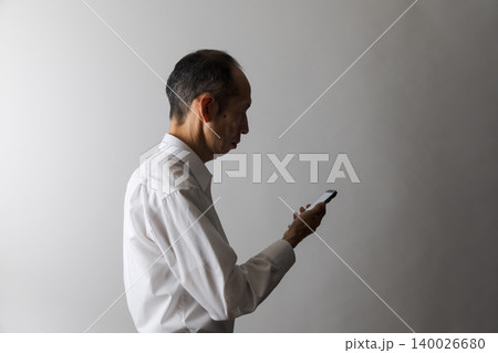 スマートフォンを見る中高年日本人男性 スマートフォンを見る中高年日本人男性 140026680