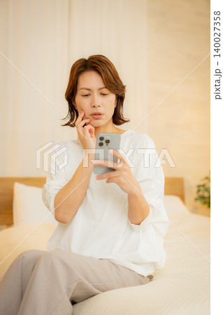 夜にスマホを見る女性 140027358