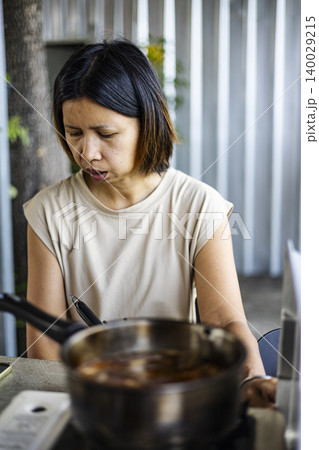 Woman Checking Phone While Waiting For Soup To Boil, female browsing smartphone in kitchen, background for smart home marketing campaign, brand awareness, domestic lifestyle and technology documentary Woman Checking Phone While Waiting For Soup To Boil, female browsing smartphone in kitchen, background for smart home marketing campaign, brand awareness, domestic lifestyle and technology documentary 140029215