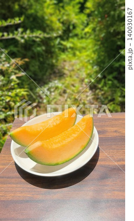 新緑が美しい屋外で撮影された白いお皿に並ぶ瑞々しい赤肉カットメロン 新緑が美しい屋外で撮影された白いお皿に並ぶ瑞々しい赤肉カットメロン 140030167