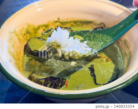ナスとチキンのグリーンカレー。青唐辛子とココナッツミルクのタイ料理。カレーに浸したお米を持ち上げてる ナスとチキンのグリーンカレー。青唐辛子とココナッツミルクのタイ料理。カレーに浸したお米を持ち上げてる 140033354