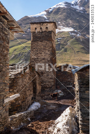 Stone tower stands tall beside ancient buildings. Ushguli in Georgia. 140033513