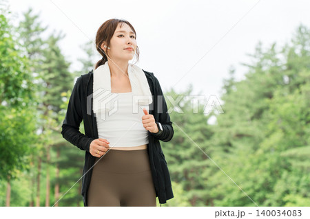 イヤホンをして公園でランニング,ウォーキング,ジョギング,運動をする女性(ダイエット,スポーツ) イヤホンをして公園でランニング,ウォーキング,ジョギング,運動をする女性(ダイエット,スポーツ) 140034083